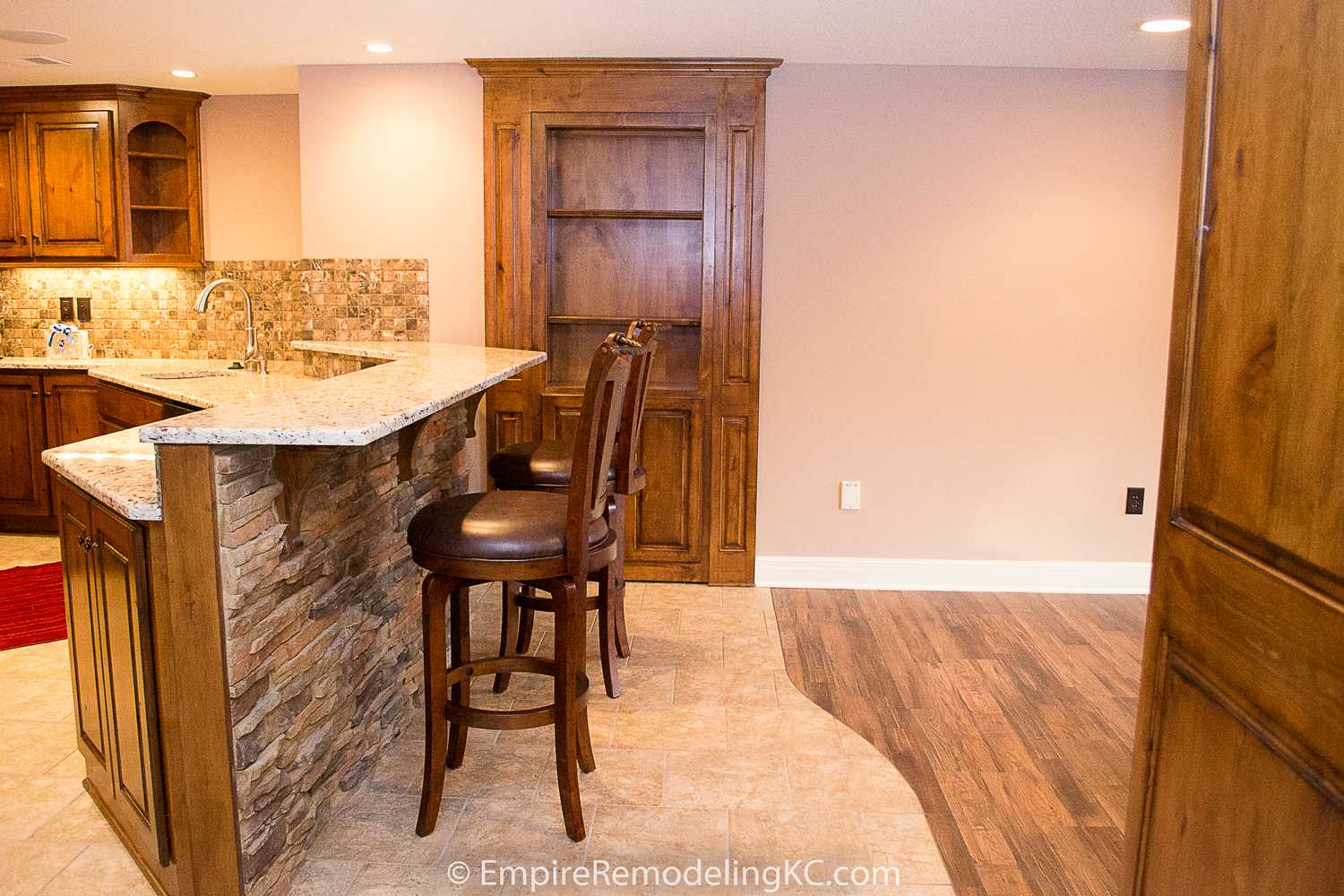 Deluxe Kitchen in Basement remodel with crawford ceilings, hidden doors, stone and granite bar, and living area.