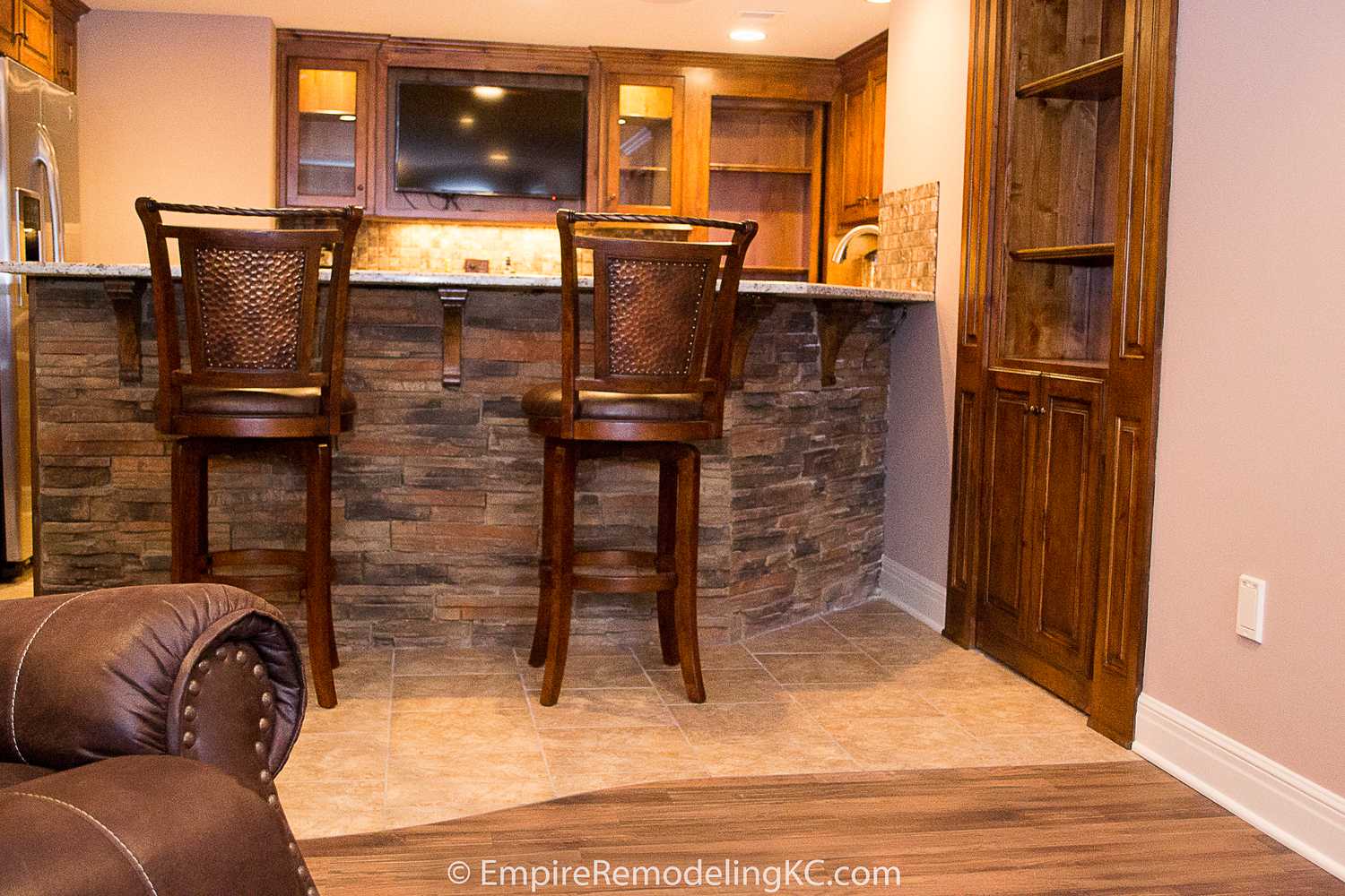 Deluxe Kitchen in Basement remodel with crawford ceilings, hidden doors, stone and granite bar, and living area.