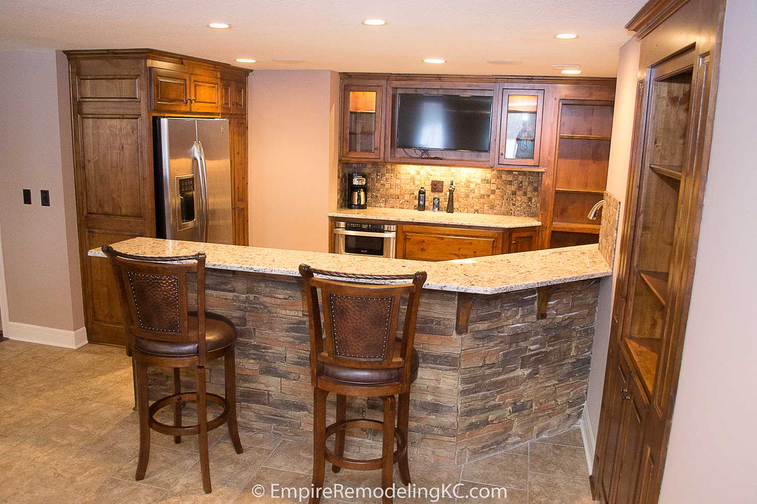 Deluxe Kitchen in Basement remodel with crawford ceilings, hidden doors, stone and granite bar, and living area.