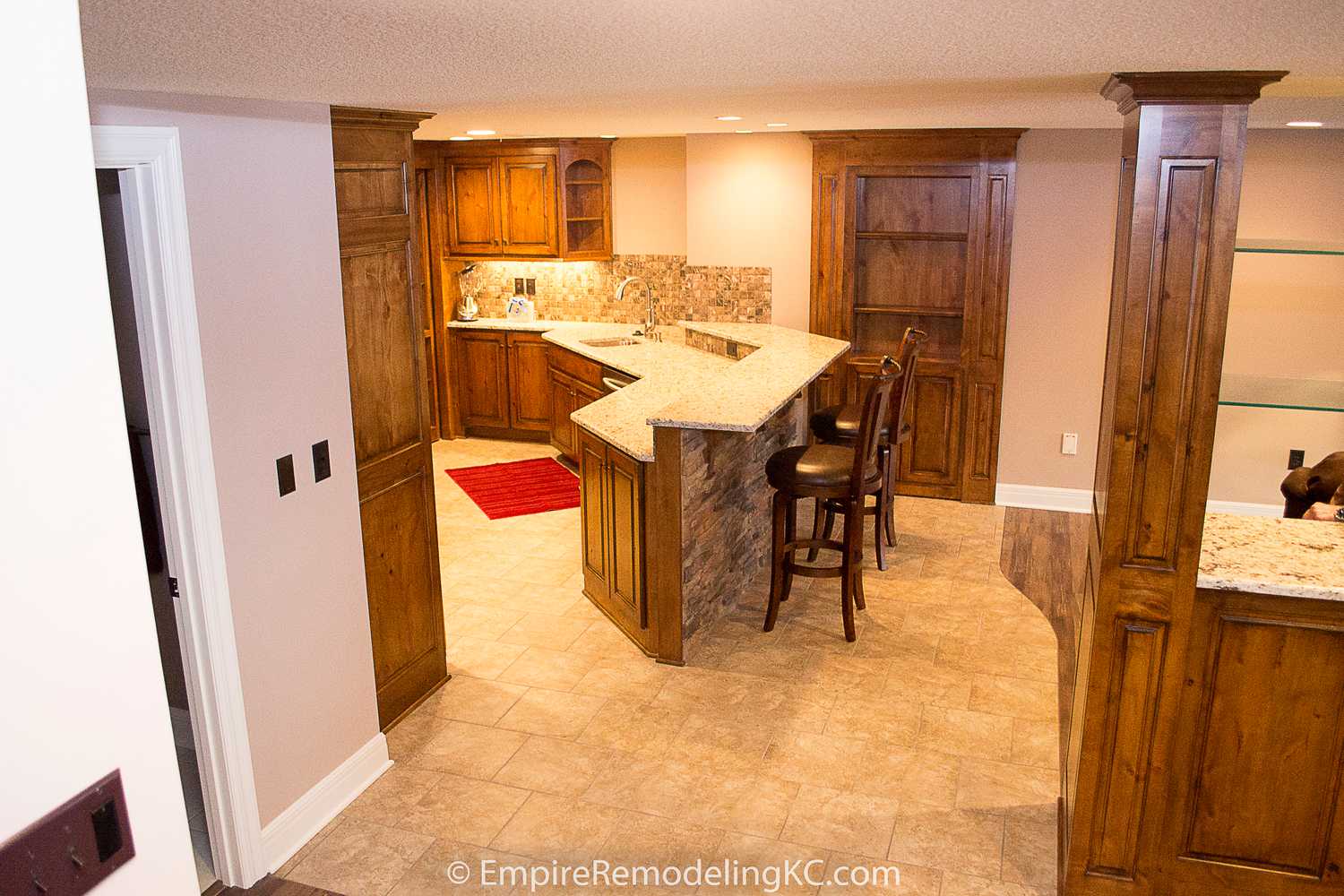 Deluxe Kitchen in Basement remodel with crawford ceilings, hidden doors, stone and granite bar, and living area.