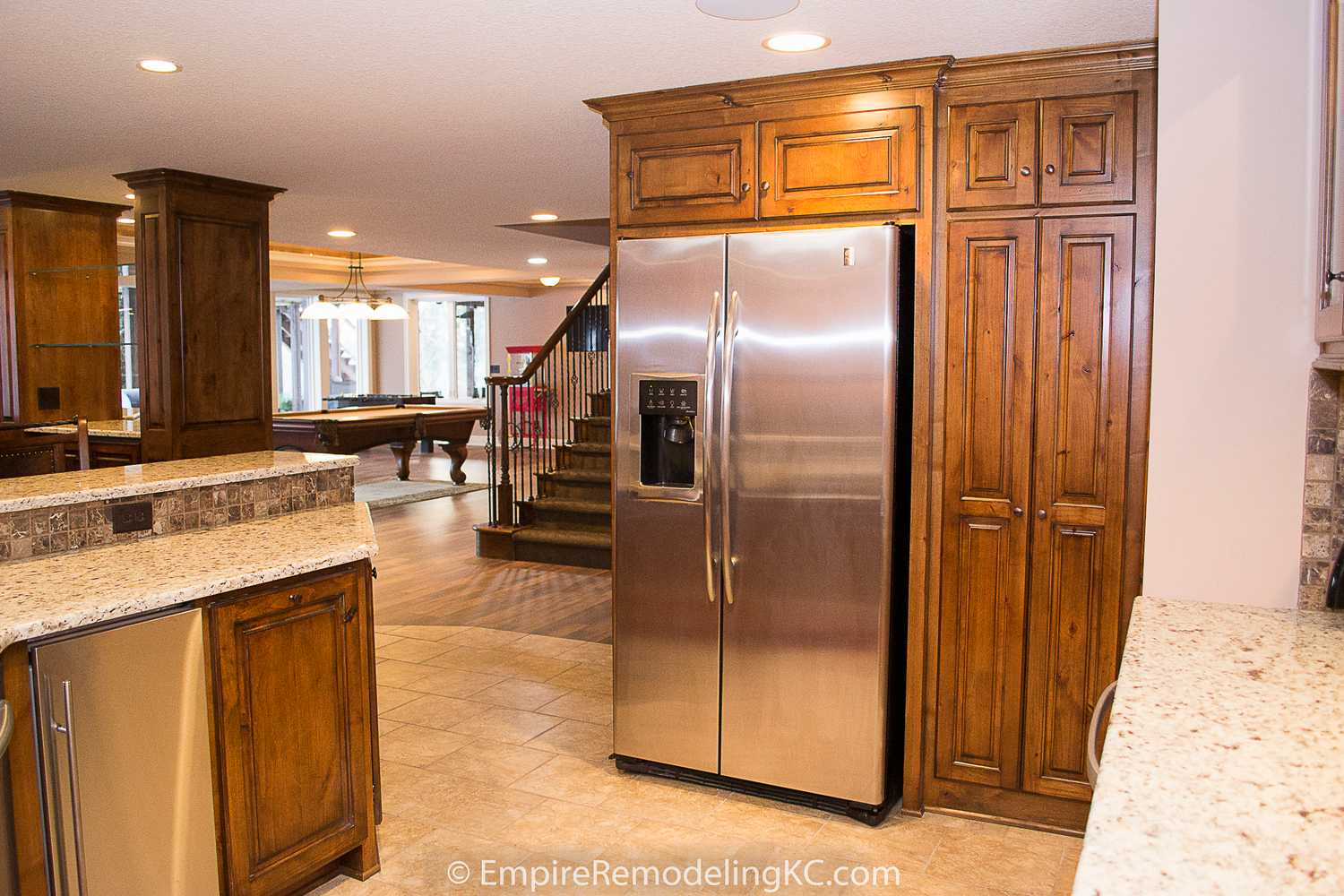 Deluxe Kitchen in Basement remodel with crawford ceilings, hidden doors, stone and granite bar, and living area.