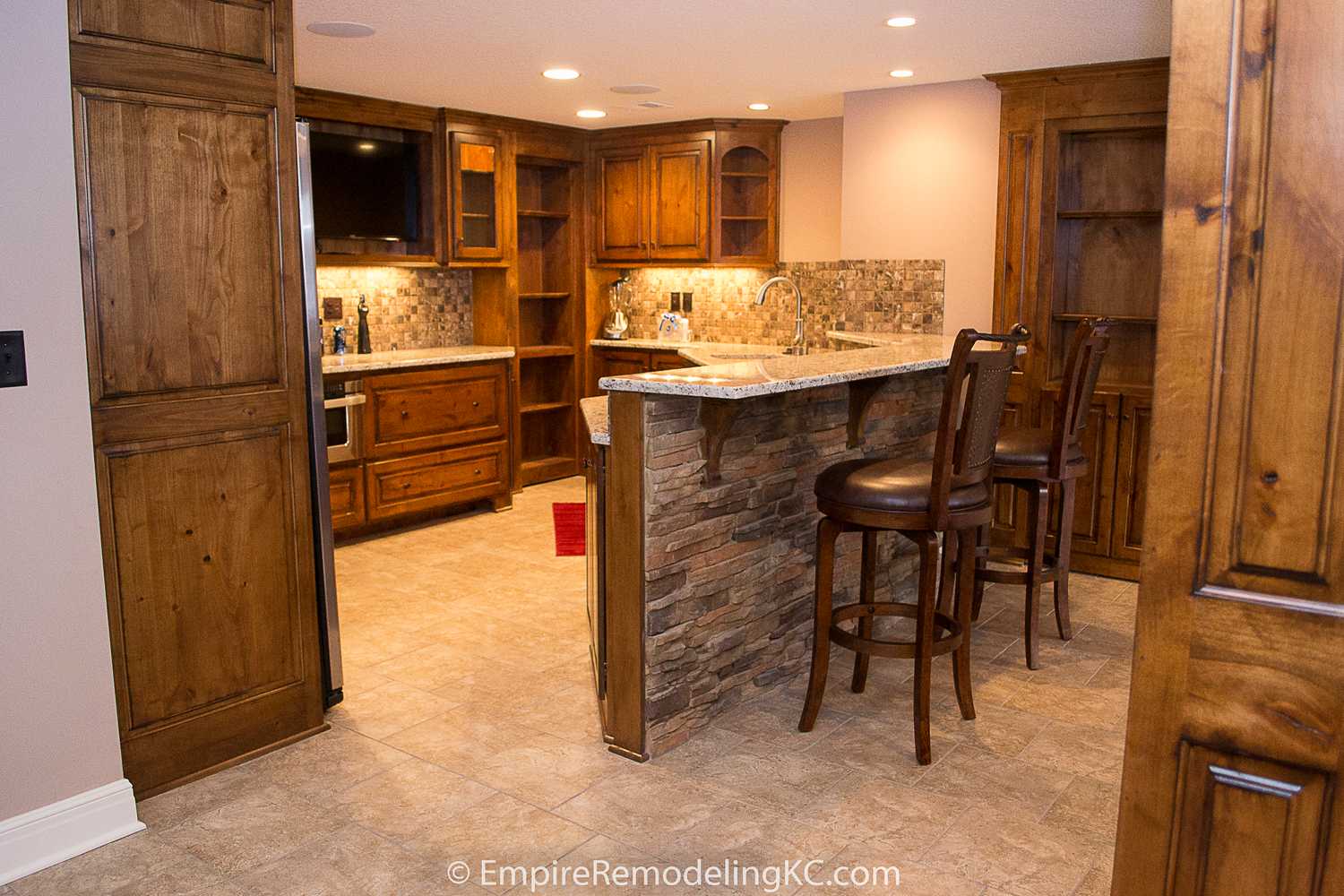 Deluxe Kitchen in Basement remodel with crawford ceilings, hidden doors, stone and granite bar, and living area.