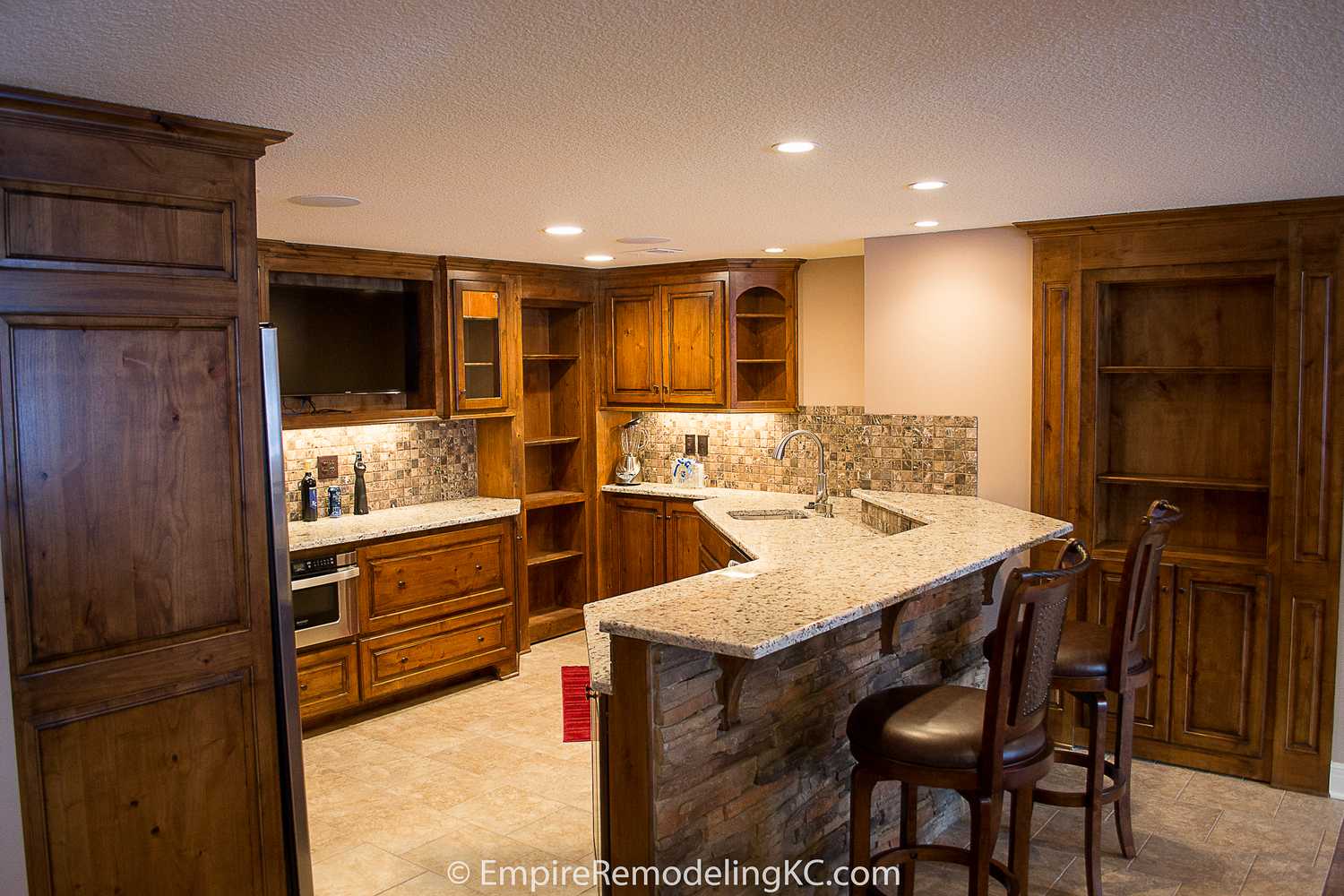 Deluxe Kitchen in Basement remodel with crawford ceilings, hidden doors, stone and granite bar, and living area.