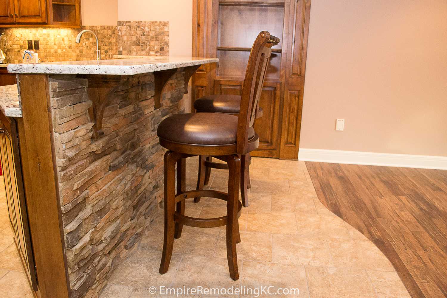 Deluxe Kitchen in Basement remodel with crawford ceilings, hidden doors, stone and granite bar, and living area.