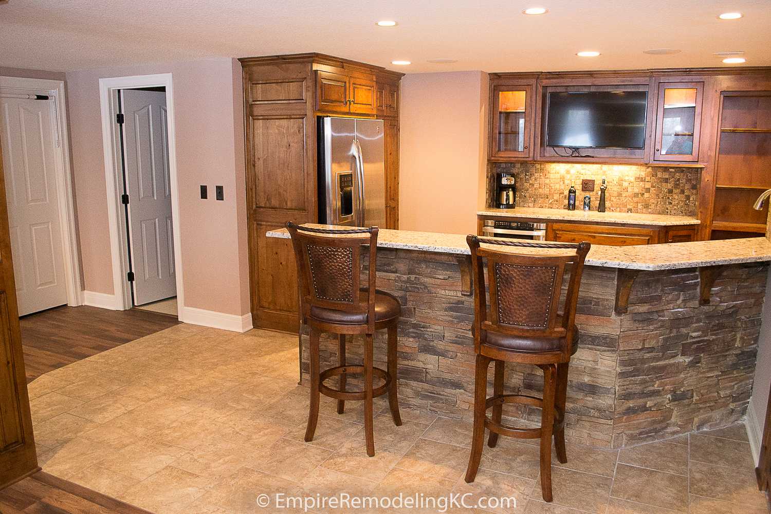 Deluxe Kitchen in Basement remodel with crawford ceilings, hidden doors, stone and granite bar, and living area.